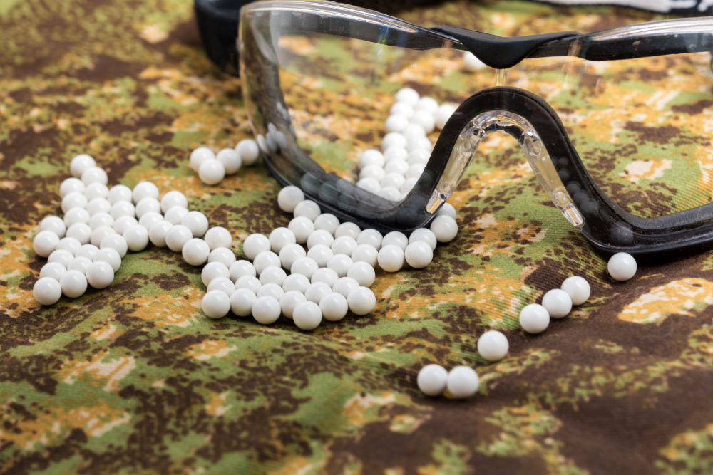 Bbs And Protective Glasses On A Camouflaged Background - Airsoft Ottawa